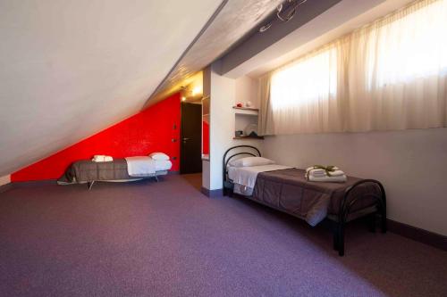 Zimmer mit 2 Betten und einer roten Wand in der Unterkunft B&B Benny in San Marco Evangelista