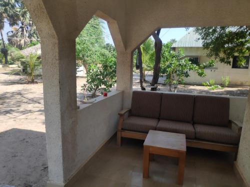 a couch and a coffee table on a porch at Mama Folonko Lodge with private Beach Paradise in Kartung