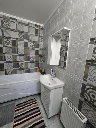 ein Badezimmer mit Waschbecken, Badewanne und Spiegel in der Unterkunft Апартаменты Астаны in Astana