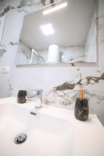 a bathroom sink with a mirror and a soap dispenser on it at Apartman Bašić in Posušje