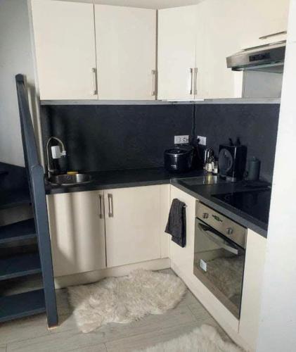 une cuisine avec des armoires blanches et un comptoir noir dans l'établissement Appartement Strasbourg centre et gare, à Strasbourg