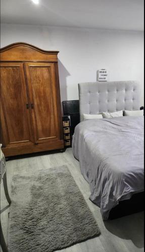 - une chambre avec un grand lit et une armoire en bois dans l'établissement Appartement Strasbourg centre et gare, à Strasbourg