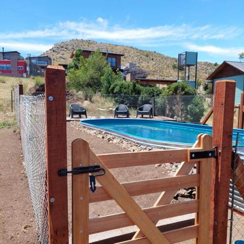 a wooden gate with a fence next to a pool at Cabaña El Pazo in Sierra de la Ventana
