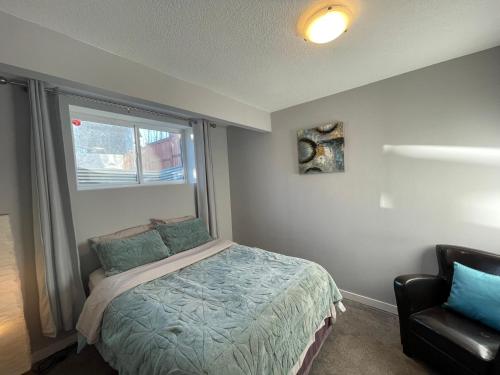 ein Schlafzimmer mit einem Bett, einem Fenster und einem Stuhl in der Unterkunft Comfortable and Beautiful Brand-New Suite BSMT-Two Bedroom, Two Washrooms in Calgary