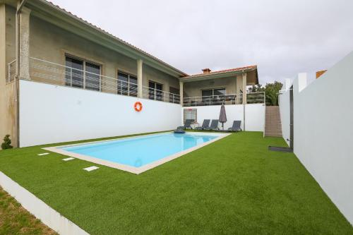 a backyard with a swimming pool and grass at CASA MARIA in Marinhas