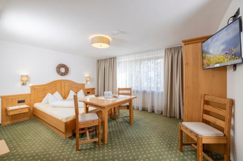 a hotel room with a bed and a table and a tv at Restaurant Gästehaus Wiesenheim in Uderns
