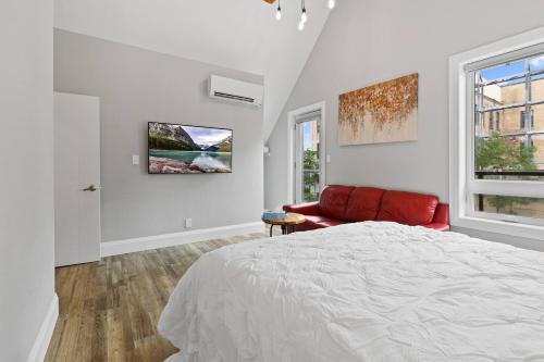 a white bedroom with a bed and a red couch at ENTIRE BACHELOR UNIT EN-SUITE ACROSS FROM GOOGLE - br4 in Kitchener