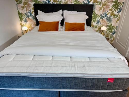 a large bed with white sheets and orange pillows at RELAX HOME Maison et studio ensemble in Deauville