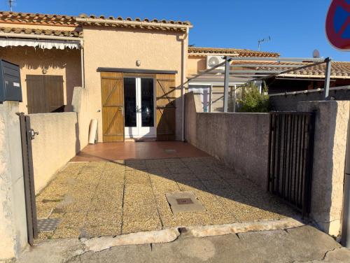 une maison avec un portail et une porte à l'avant dans l'établissement Maison Cosy Plage à 10 min, Parking, Climatisation, Wi-Fi, à Saint Cyprien Plage