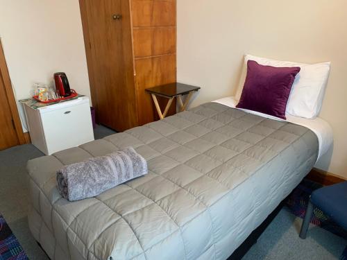 a bedroom with a large bed with purple and white pillows at Thomas's Catlins Lodge and Camp Ground in Owaka