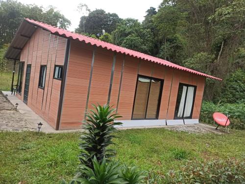 een klein huis met een rood dak en een rode stoel bij Villa café in Vergara