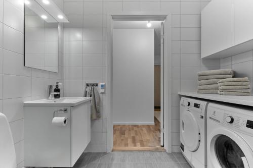 a white bathroom with a washing machine and a sink at The Pink Patio - Cozy Modern Private Apartment in Solna