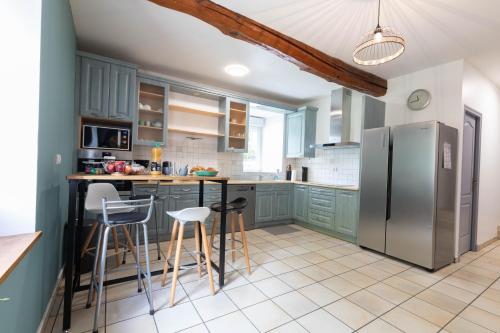 La cuisine est équipée d'armoires vertes et d'un réfrigérateur en acier inoxydable. dans l'établissement La grange des Thermes, à Beaucens