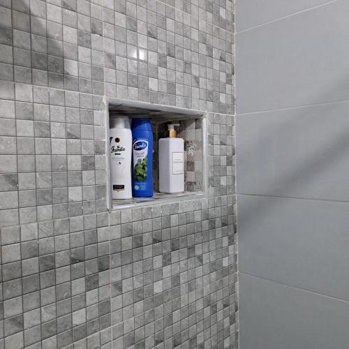 a shelf in a tiled bathroom with toiletries on it at Appartement Neuf Excellent Rapport Qualité Prix CHU TANGER Forêt Diplomatique IBN Batouta in Daidatz