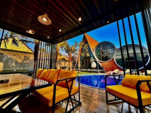 a living room with a table and chairs and a pool at Qafqaz Rolling Bungalow HOT POOL in Gabala