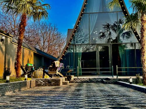 a building with palm trees in front of it at Qafqaz Rolling Bungalow HOT POOL in Gabala