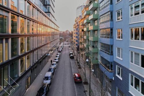 a city street with cars parked next to tall buildings at The Pink Patio - Cozy Modern Private Apartment in Solna
