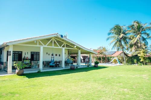 a white house with a palm tree in the background at Recanto Preocupação Zero in Morro Branco