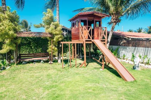 a tree house with a slide in a yard at Recanto Preocupação Zero in Morro Branco