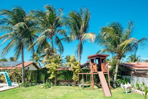 a playground in front of a house with palm trees at Recanto Preocupação Zero in Morro Branco