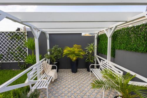 a patio with two white benches and plants at VILLA HELENA Crystal Apartment in Caniço