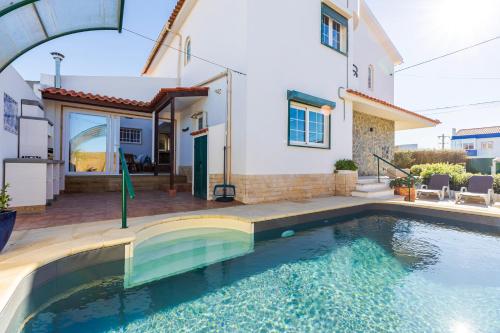 a house with a swimming pool in front of a house at Casa Brincosa Ericeira in Ericeira
