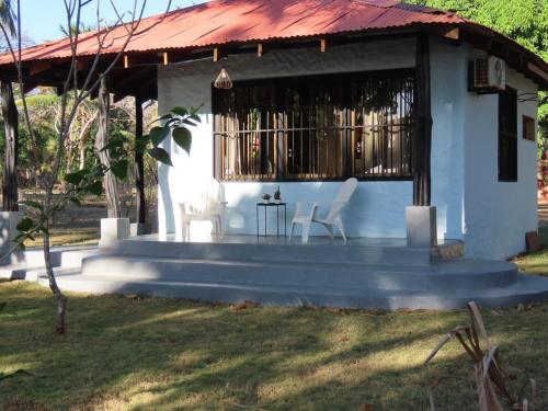 a house with a porch and two white chairs at Casita Frente al Mar in Cuajiniquil
