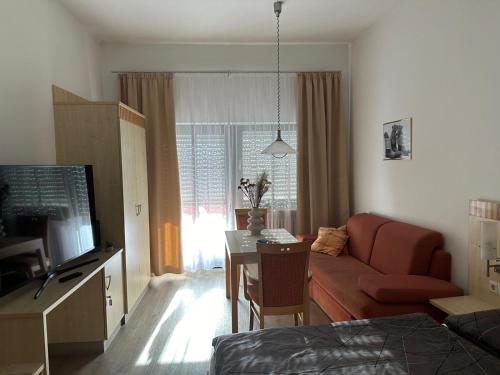 a living room with a red couch and a table at Appartement mit Bademantelgang zur Wohlfühltherme in Bad Griesbach