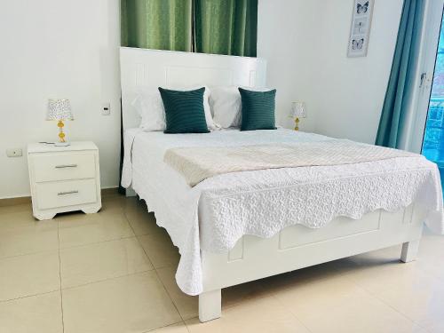 una camera da letto con un letto bianco con cuscini verdi di Cozy condo 290m distance from the beach a Punta Cana