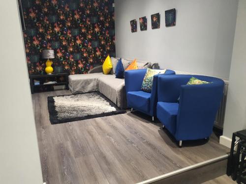 a living room with two blue chairs and a couch at Saphire Glasgow Apartments in Giffnock