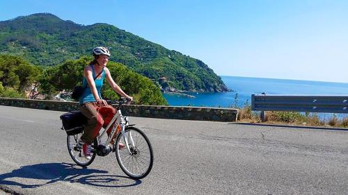 a woman riding a bike down a road at Studio Paola - Levanto in Levanto