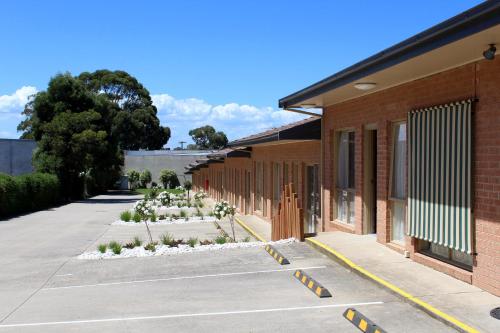 a row of buildings with white flowers in a parking lot at Cranbourne Motor Inn in Cranbourne