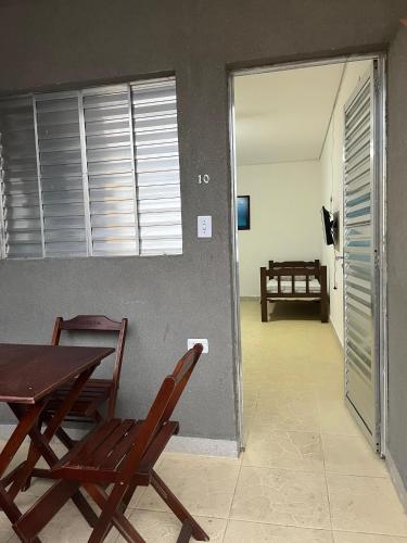 a dining room with a table and two chairs and a room at Vila Mar Suítes in Bertioga
