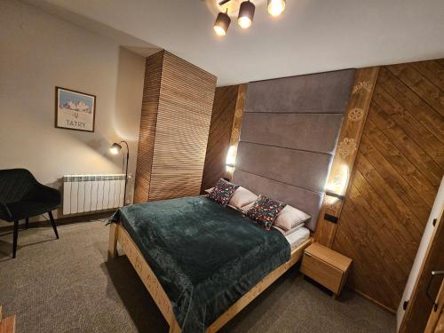 a bedroom with a bed and a chair in it at Apartament SKUPNIOWY UPŁAZ in Murzasichle