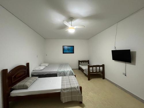 a bedroom with two beds and a flat screen tv at Vila Mar Suítes in Bertioga