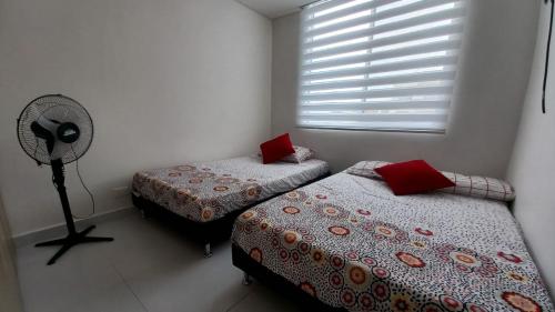 two beds in a room with a fan and a window at Hacienda Peñalisa Bambu Girardot-Ricaurte in Soacha