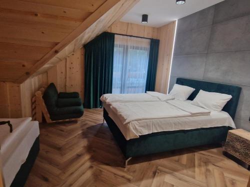 a bedroom with a large bed and a chair at Chata Braci Warchały in Warchały