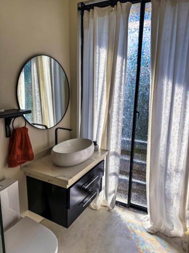 a bathroom with a sink and a mirror and a window at Kaleidoscopic Apartment in La Majagua