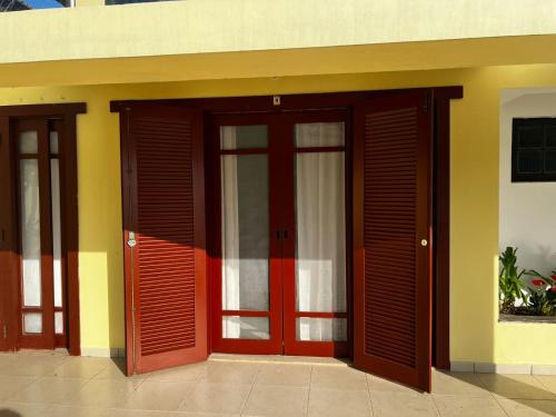 a building with red doors and yellow at Pousada Vitória Régia - Hotel Costeira in São Sebastião