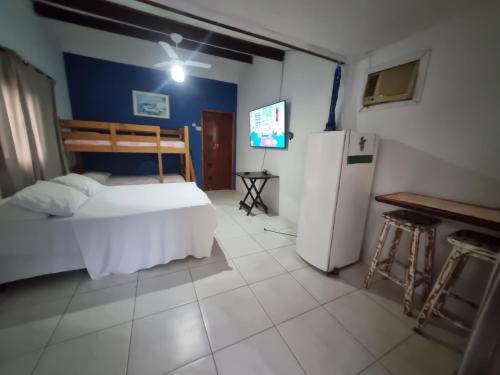 a bedroom with a white bed and a refrigerator at Pousada Brilho De Paraty in Paraty