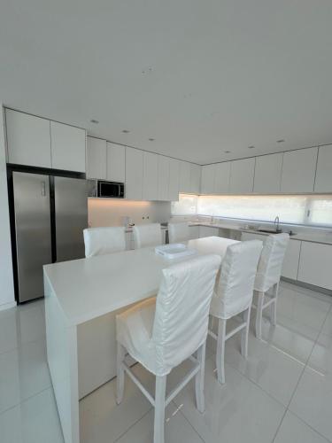 eine Küche mit einem weißen Tisch und weißen Stühlen in der Unterkunft Serena Boutique Potrero Garay in Potrero de Garay