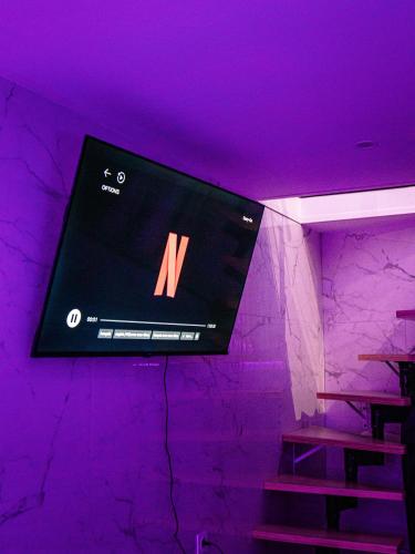a tv hanging on a wall with a purple ceiling at Suite KING Size SAUNA JACUZZI in Lisieux