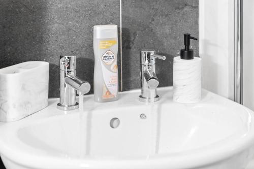 a bathroom sink with two faucets and a mirror at Harmony House 3 Bedroom New Build for Families, Contractors, Black Country Museum Sleeps 6 in Tipton