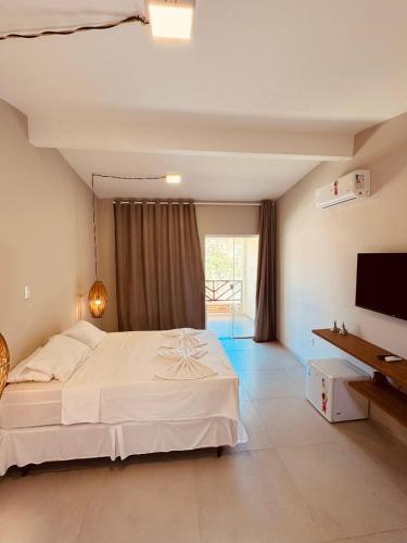 a bedroom with a large bed and a television at Pousada Villa Manzuá in Cascavel