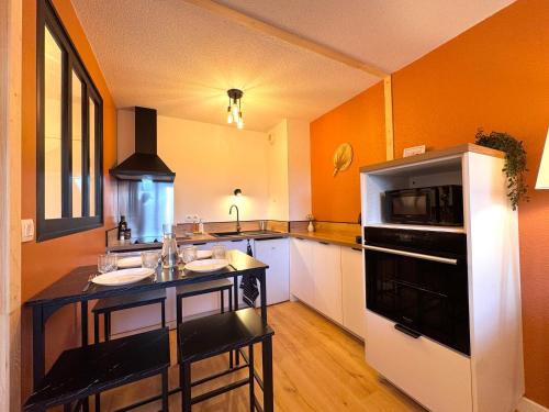 - une cuisine avec des murs orange et un réfrigérateur noir et blanc dans l'établissement Appartement Graulhet le nid de carivel, à Graulhet