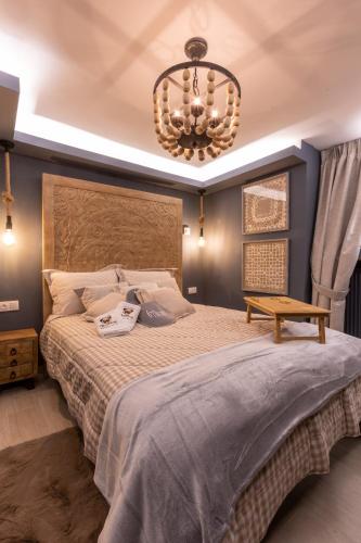 a bedroom with a large bed and a chandelier at Rock Dandy La Maison de l'Ours - Nymfaio in Nimfaíon