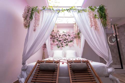- une chambre dotée d'un lit avec des rideaux blancs et des fleurs dans l'établissement Cocon des Merveilles - balnéo ronde avec cascade, au Havre