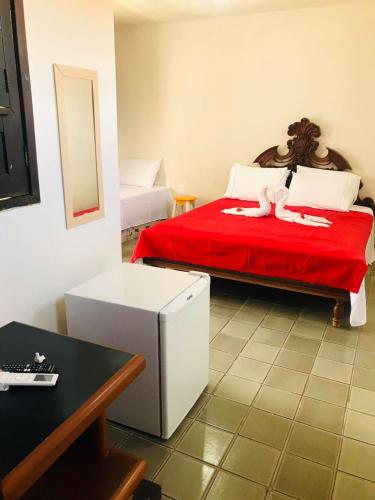 a bedroom with a bed with red sheets and a red blanket at Pousada Bella Maré in Goiana