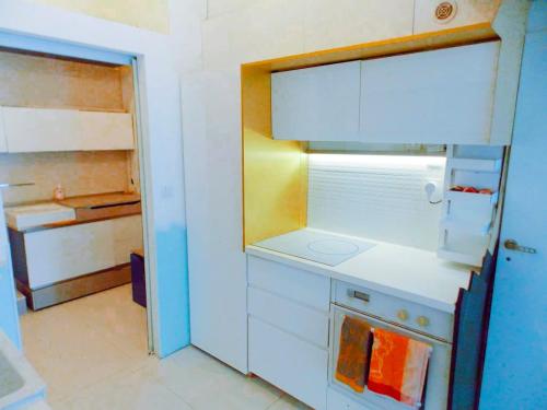 une cuisine avec des armoires blanches et une porte ouverte dans l'établissement Loft atypique, au calme, à Montpellier