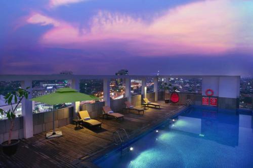 einen Pool auf dem Dach mit Blick auf die Stadt in der Nacht in der Unterkunft ASTON Imperial Bekasi Hotel & Conference Center in Bekasi